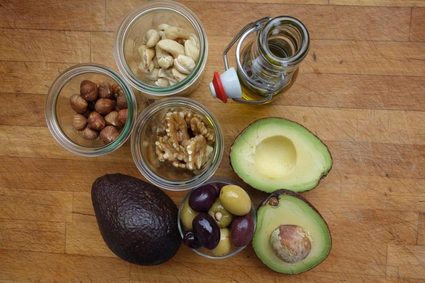 Frutos secos sobre una mesa juntos con aguacate y aceite de olivas.