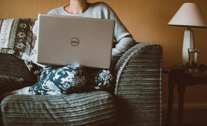 Mujer descansando en un sillón con una laptop.