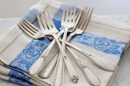 Vintage silver forks on a blue and white cloth.