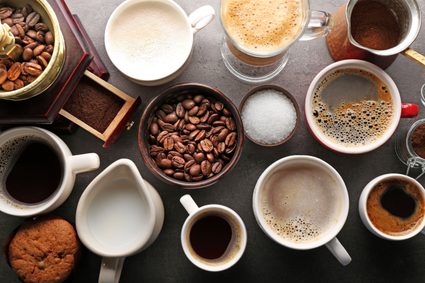 Various types of coffee drinks and coffee beans on a table.