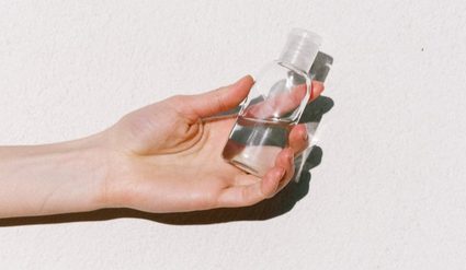 Hands and a hand sanitizer in a reusable bottle