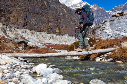 A man crossing a creek on a wooden plank