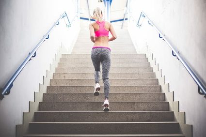 Calcolatore per le calorie bruciate salendo le scale: donna che fa jogging al piano superiore.
