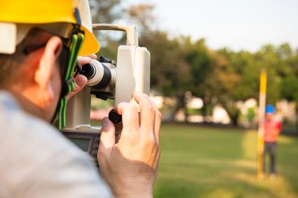 Land surveyor viewing a leveling rod through a surveyor's transit.